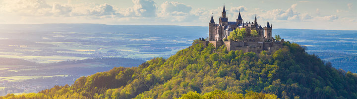 Kasteel Hohenzollern op een beboste heuvel in Duitsland, uitkijkend over het landschap.