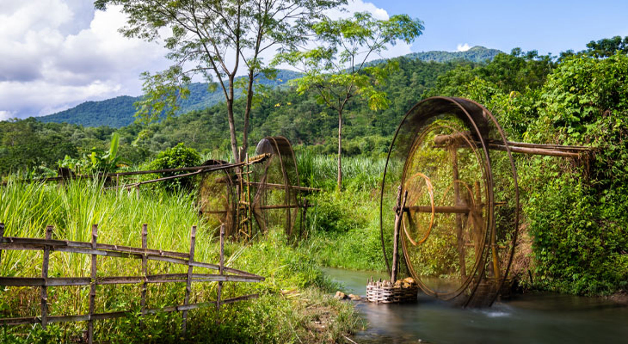 Mai Chau Traditionele bamboe waterwielen langs een rivier in het groene berglandschap van Vietnam.