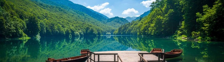 Uitzicht over een bergmeer met houten steiger en bootjes in Bosnië en Herzegovina.