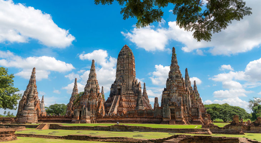 Wat Chaiwatthanaram-tempelruïnes in Ayutthaya, Thailand, met hoge prangs onder een blauwe lucht.