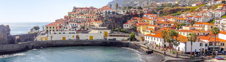 Kustplaats in Portugal met kleurrijke huizen en rode daken rond een beschutte baai.