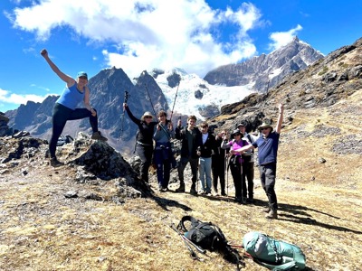 Gezin wandelt in de Andes in Peru met trekkingstokken, met besneeuwde bergtoppen op de achtergrond.