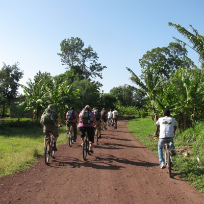 Fietstocht over een rode zandweg langs bananenbomen in Tanzania tijdens de route Kenia, Tanzania en Zanzibar.