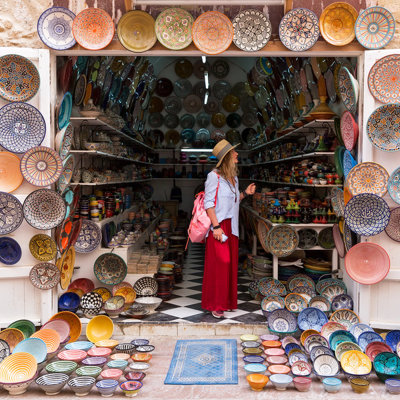 Reiziger in Marokkaanse souk bij winkel vol kleurrijk aardewerk en schalen tijdens groepsrondreis Marokko Kort.