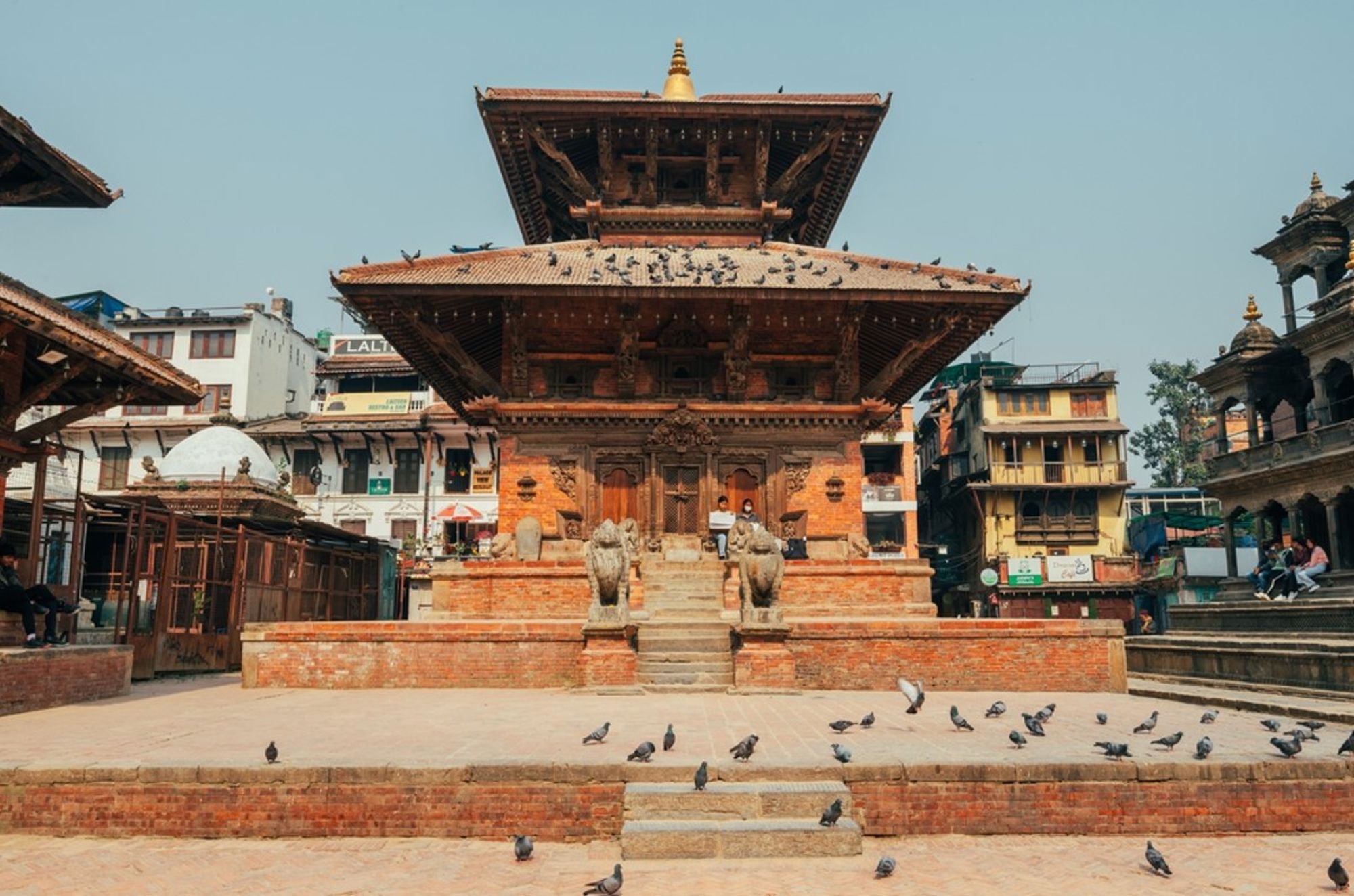 Traditionele pagode op Durbar Square in Kathmandu, Nepal, met stenen leeuwen en duiven op het plein.