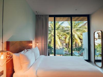 Moderne hotelkamer in Calixta hotel met tweepersoonsbed en balkon met uitzicht op palmbomen.