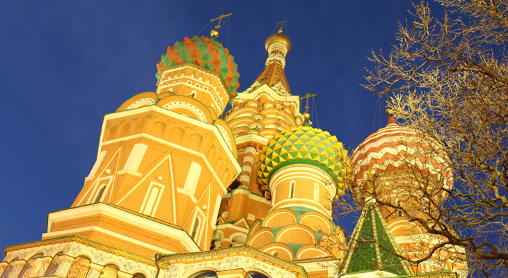 Verlichte koepels van de Basiliuskathedraal op het Rode Plein in Moskou bij avondlicht.