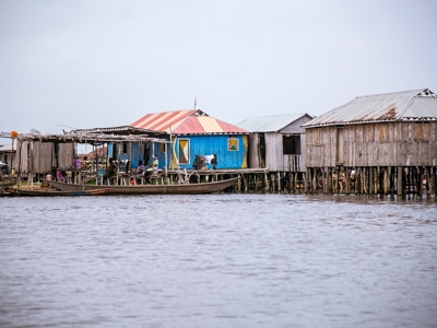 Houten paalwoningen aan het water met kano’s voor de kust, tijdens een reisroute door Ghana, Togo en Benin.