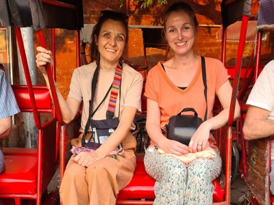 Twee reizigers in een rode fietstaxi tijdens de route door Noord-India.